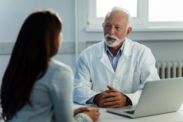 Medico senior che parla con una paziente durante le consultazioni mediche presso l'ufficio del medico