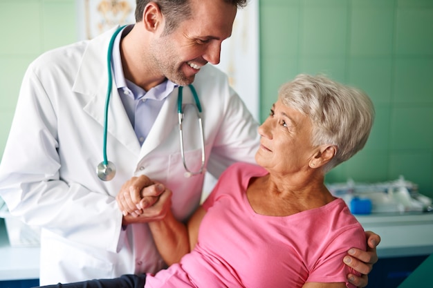 Medico sorridente che aiuta della donna maggiore