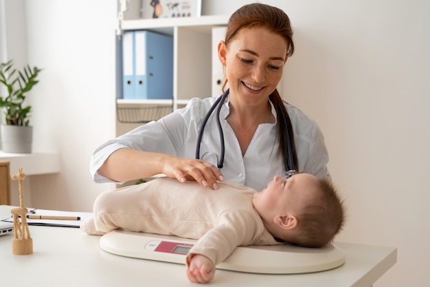 Medico sorridente del colpo medio che pesa bambino