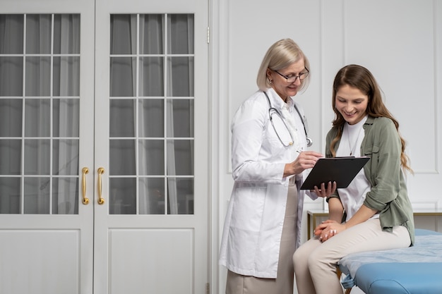 Medico sorridente del tiro medio e chat del paziente