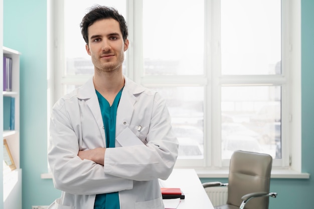 Medico sorridente di tiro medio con le braccia incrociate