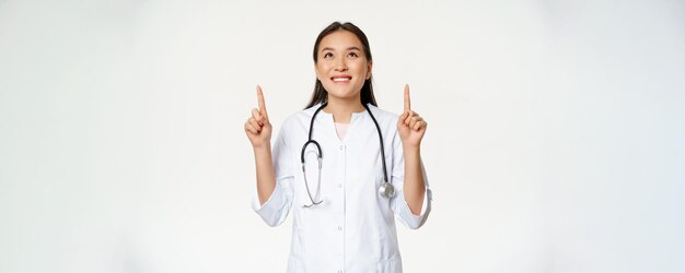Medico sorridente felice della donna asiatica del medico che osserva in su con l'espressione allegra del fronte che porta medico