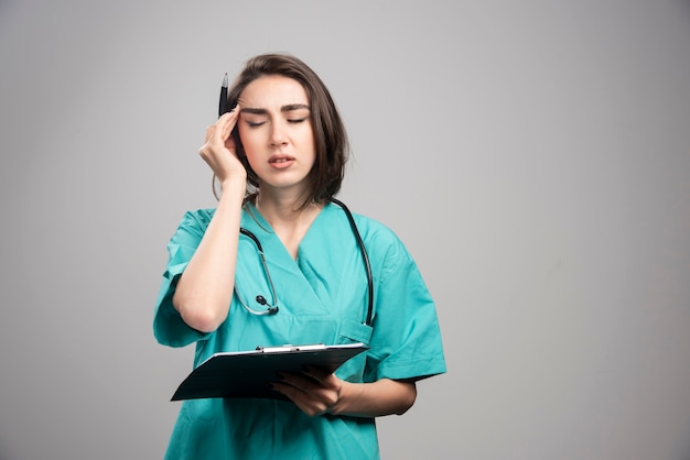 Medico stanco che ha mal di testa su sfondo grigio. Foto di alta qualità