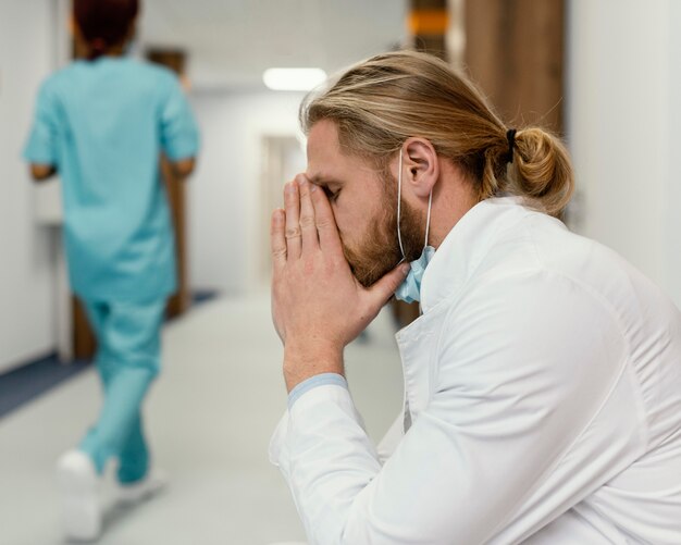 Medico stanco del colpo medio con la maschera