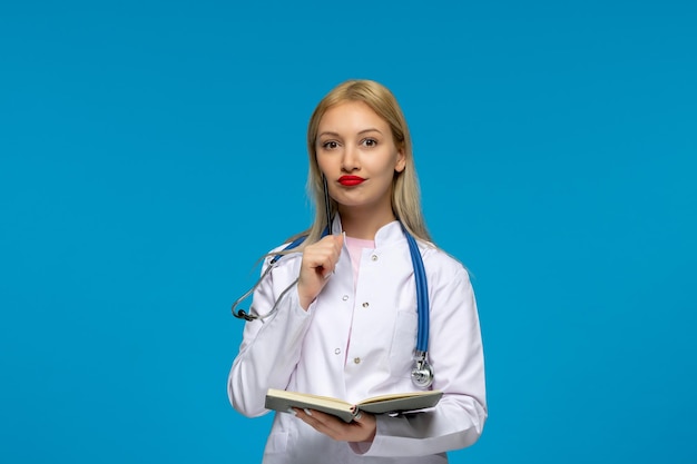 Medico sveglio della giornata mondiale dei medici che tiene un taccuino con lo stetoscopio nel camice