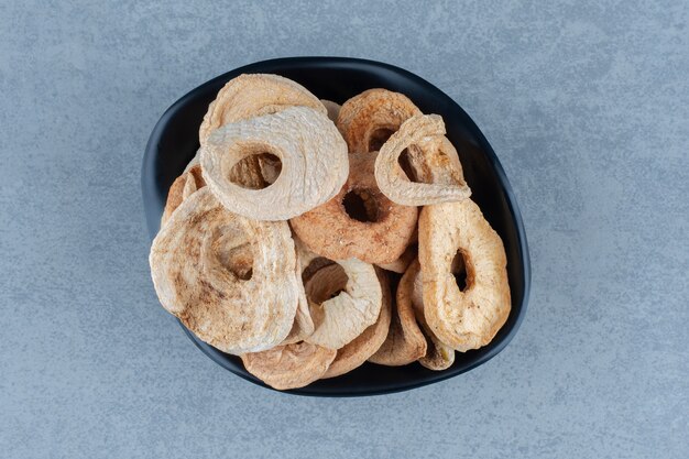 Mela secca appetitosa nella ciotola, sul tavolo di marmo.