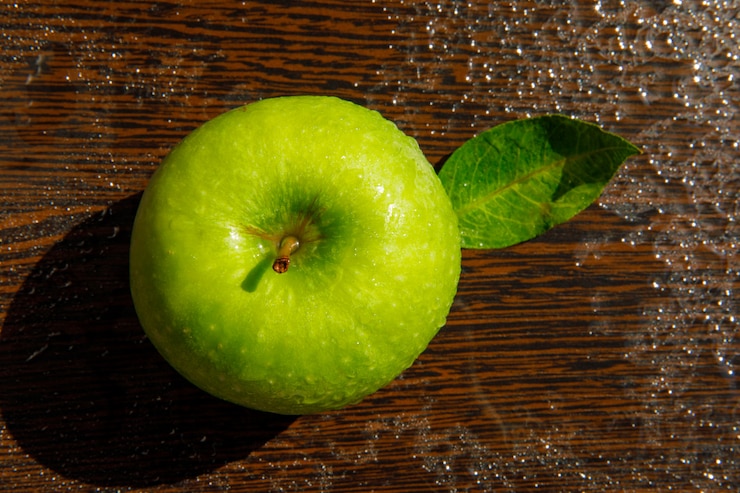 Foto gratuito mela verde con foglia su legno scuro piovoso. disteso.