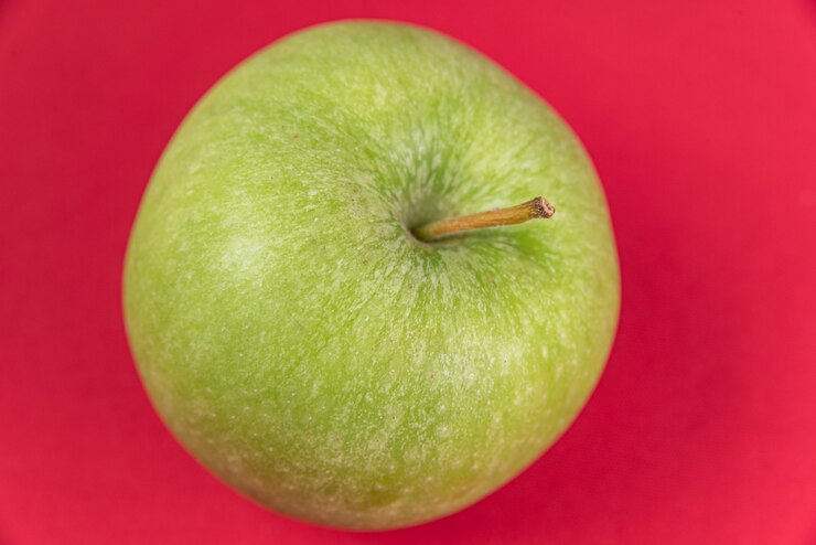 Foto gratuito mela verde su sfondo rosso