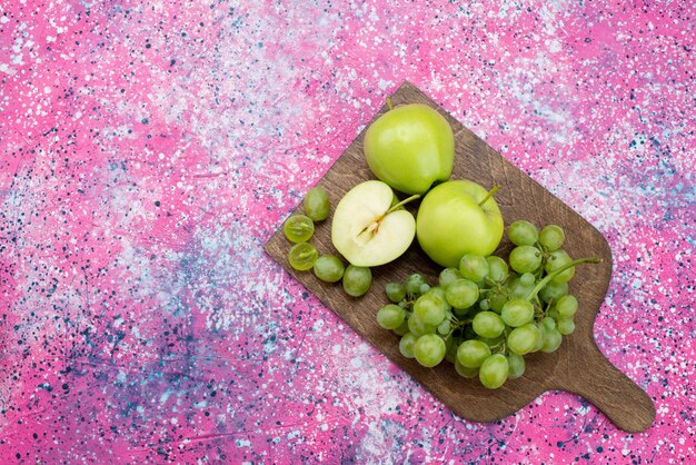 Mele verdi di vista superiore e uva verde sulla foto a colori maturi maturi della frutta viola dello scrittorio