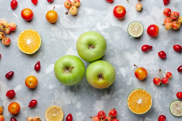 Mele verdi fresche di vista superiore con il limone e le ciliegie sullo scrittorio bianco frutta bacca vitamina estate mellow