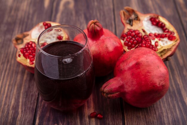 Melograni di vista frontale con un bicchiere di succo su una parete di legno