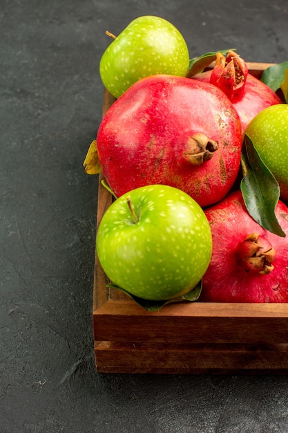 Melograni rossi freschi di vista frontale con le mele verdi sul colore della frutta matura di superficie scura