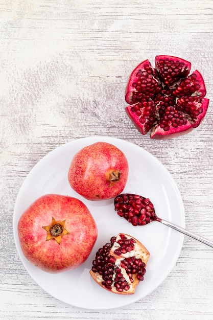 Melograno di vista superiore sul piatto bianco e succo di melograno sulla tavola di legno