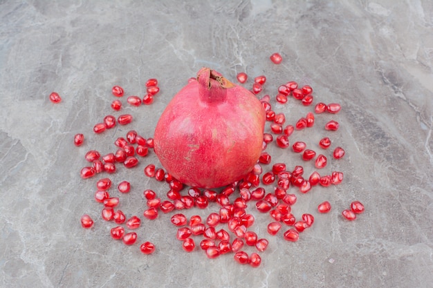 Melograno rosso e semi su sfondo di pietra.