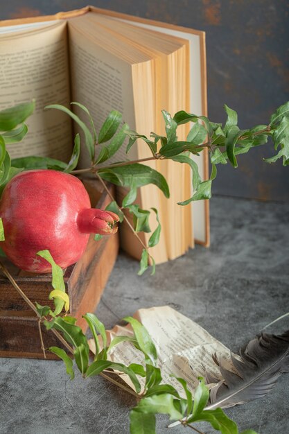 Melograno rosso in scatola di legno con libro e foglie