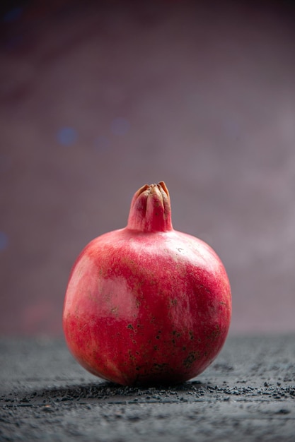 Melograno rosso maturo del melograno rosso di vista laterale sulla tavola grigia su fondo porpora