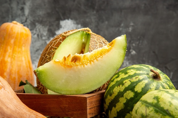 Melone fresco vista frontale con zucca e anguria su sfondo scuro