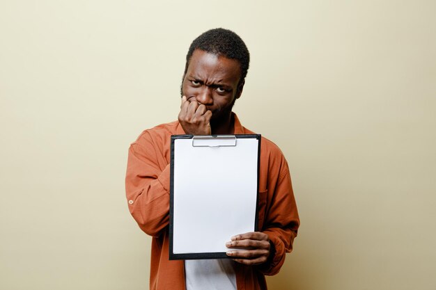 Mento teso afferrato giovane maschio afroamericano che tiene appunti isolato su sfondo bianco