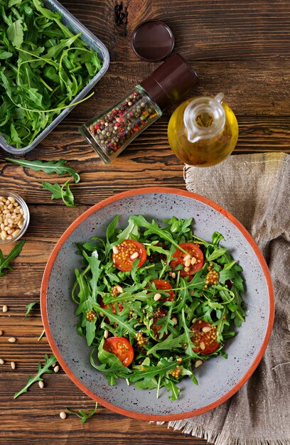 Menu dietetico. Cucina vegana. Sana insalata con rucola, pomodori e pinoli. Disteso. Vista dall'alto