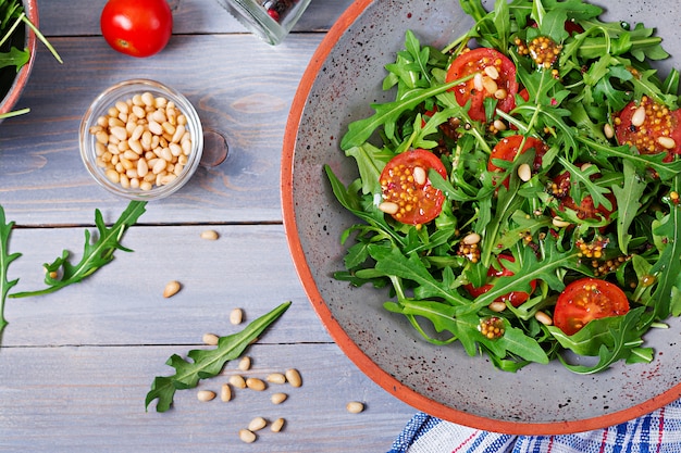 Menu dietetico. Cucina vegana. Sana insalata con rucola, pomodori e pinoli. Disteso. Vista dall'alto