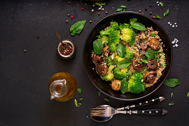 Menu dietetico. Insalata vegana sana di verdure - broccoli, funghi, spinaci e quinoa in una ciotola. Disteso. Vista dall'alto