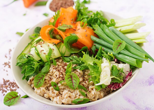 Menu dietetico. Uno stile di vita sano. Porridge di avena e verdure fresche con sedano, spinaci, cetriolo, carota e cipolla sul piatto.
