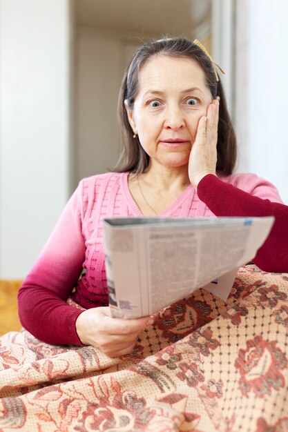 meravigliata donna che ha dolore dopo aver letto il giornale