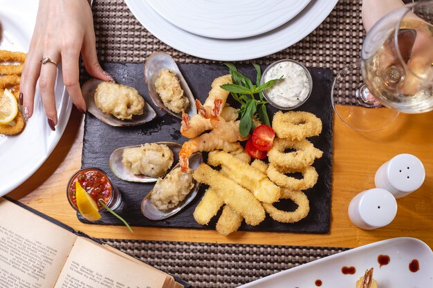 Mescolare il piatto di frutti di mare calamari gamberi cozze limone salsa tartara pomodoro menta vista dall'alto