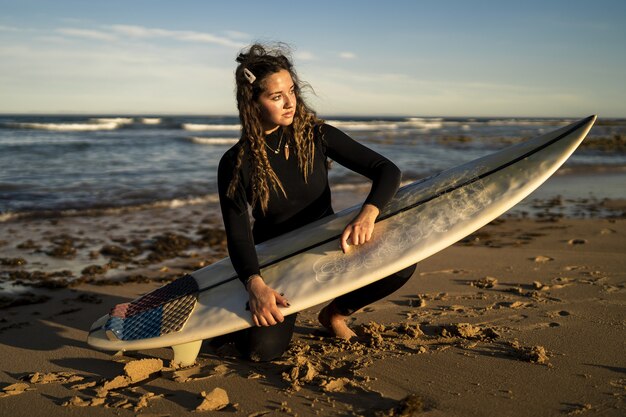 Messa a fuoco poco profonda di una donna attraente che si incera la sua tavola da surf in spiaggia in Spagna