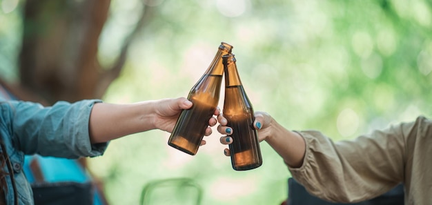 Messa a fuoco selettiva e primo piano Mani di donna e amici che si rilassano davanti alla tenda da campeggio Si divertono a tifare e bere birra divertendosi e felici insieme