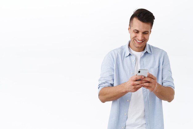 Messaggistica di comunicazione e concetto di stile di vita online Uomo bello allegro che invia messaggi di testo con un amico chat con persone che utilizzano l'applicazione per smartphone tenendo il telefono cellulare e guardano con un sorriso soddisfatto