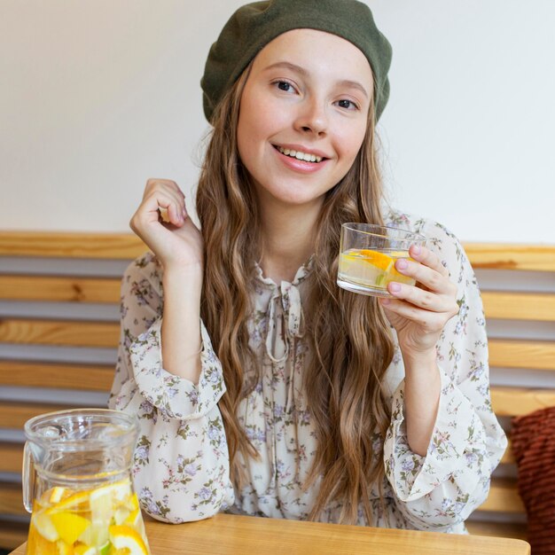 Metà colpo bella donna seduta al tavolo con bicchiere di limonata