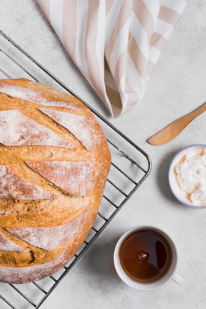 Metà del pane bianco tondo e tazza di tè distesi