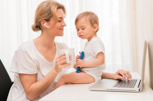 Metà di caffè e bambino beventi della donna del colpo sullo scrittorio