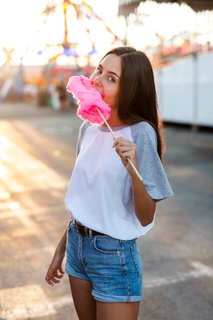 Metà di colpo donna che mangia zucchero filato rosa