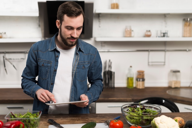 Foto gratuito metà di compressa della tenuta dell'uomo del colpo in cucina