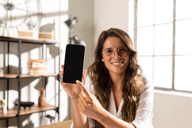 Metà di donna del colpo che mostra telefono