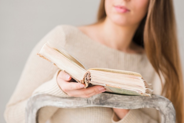 Metà di sezione della donna che tiene in mano un libro aperto