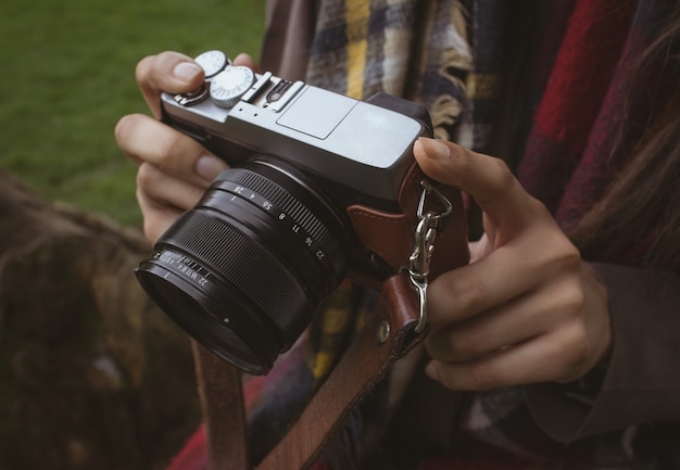 Metà di sezione della donna che tiene macchina fotografica digitale