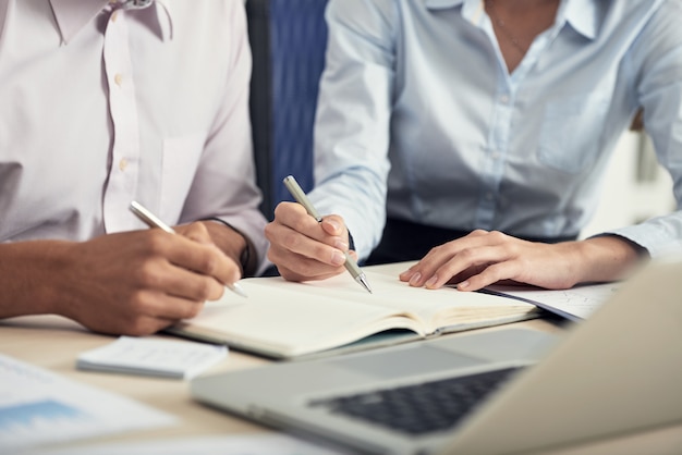 Metà di sezione di due colleghi che fanno brainstorming e prendono appunti