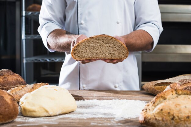 Metà di sezione di un panettiere maschio che tiene pane