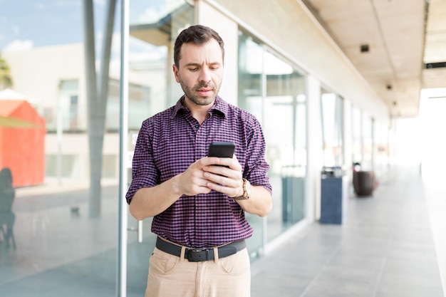 Metà uomo adulto che legge e-paper sullo smartphone mentre si trova nel centro commerciale