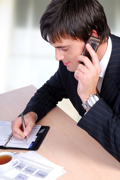 Metà uomo adulto che parla su un telefono e scrive nell'organizzatore.