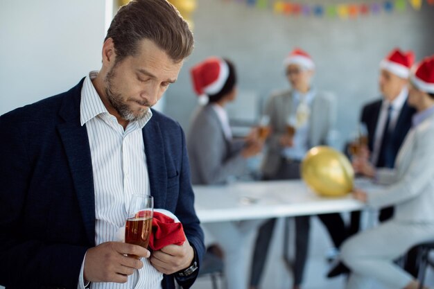 Metà uomo d'affari adulto sentirsi triste mentre è alla festa di Natale in ufficio