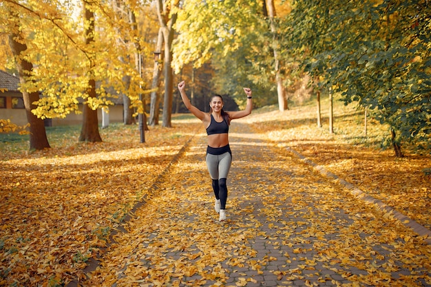 Mette in mostra la ragazza in un addestramento superiore nero in un parco di autunno