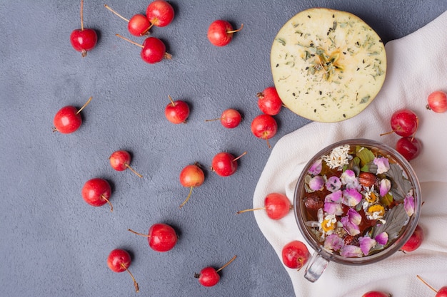 Mezza frutta tagliata, ciliegie e bicchiere di succo con fetta di limone e fiori su blu con tovaglia