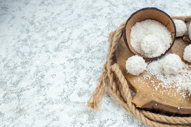 Mezza vista inferiore ciotola di polvere di cocco palline di cocco su tavola di legno su sfondo grigio