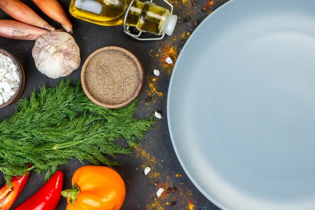 Mezza vista superiore del piatto tondo grigio verdure fresche e altri alimenti al buio