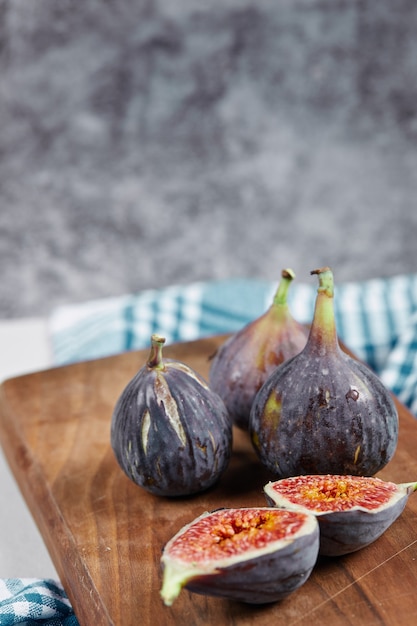 Mezze fette e fichi interi su tavola di legno con una tovaglia blu.