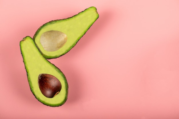 Mezzi avocado verdi isolati sulla parete rosa, con e senza seme